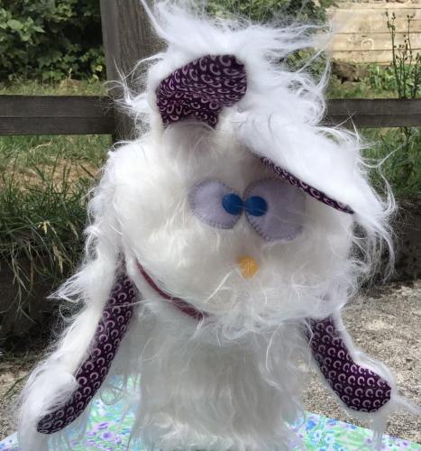 Marionnette lapin à longs poils blanc qui sourit au vent. 